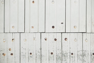 Painted old wooden dirty white fence made of boards with rusty nails and peeling paint. Light...