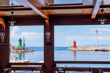 View of the little port with its light houses from a seafront restaurant (Giglio island, Grosseto, Italy).