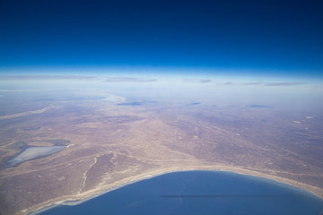 The shore of the sea lake from the porthole of an airplane on a sunny day.