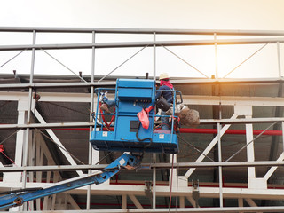 construction worker at construction site using lifting boom machinery