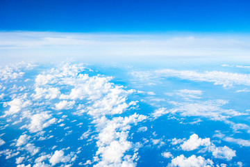 Beautiful clouds top view on a background of blue sky from the porthole of an airplane at altitude.