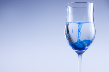 Blue color ink in glass with water. Food color, blue splash.