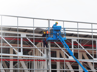 construction worker at construction site using lifting boom machinery