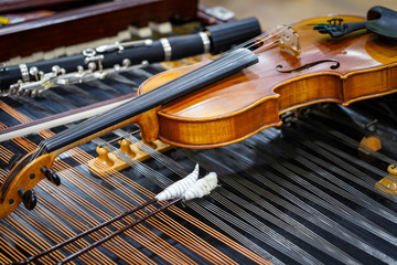 Antique violin and violin bow lying on dulcimer. Close up a violin instrument and cymbal before a concert. Music concept background