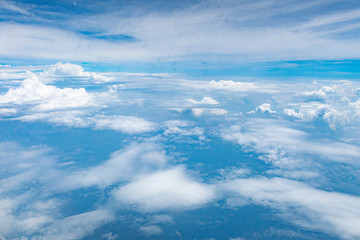 Beautiful clouds top view on a background of blue sky from the porthole of an airplane at altitude.