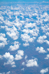 Beautiful clouds top view on a background of blue sky from the porthole of an airplane at altitude.
