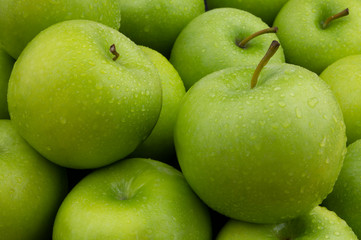 Many green apples with water drops