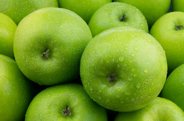 Green apples with water drops as background