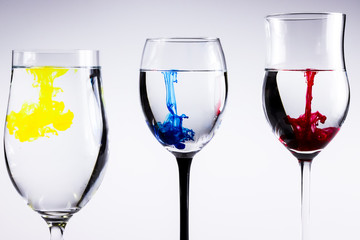 Three glasses whit ink drops. Color splash in water, isolated