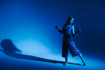 Naklejka premium Young stylish girl dancing in the Studio on a colored neon background. Classic dancer.