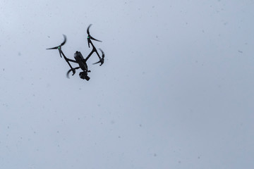 Modern RC drone flying on snow weather. Digital technology. Uav drone copter flying with digital camera in bad weather conditions. Cold, snow, blizzard. Aerial photography.