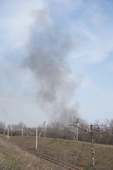 Obraz premium Black smoke in the sky above the railway.
