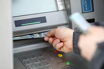 Male hands holding bunch of hundred dollars banknotes at atm machine - obrazy, fototapety, plakaty