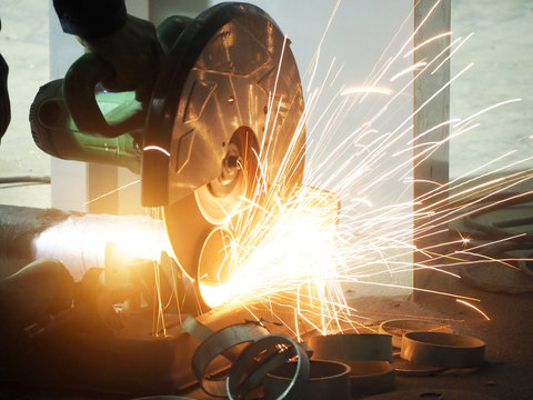 Worker grinds the steel of angular grinding machine