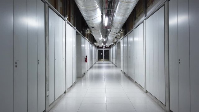 Slow walk down an empty artificially lit corridor inside industrial building stabilized