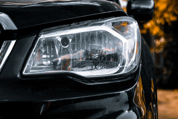 Left front headlight of black SUV. Headlights of a black car