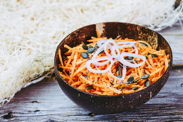 Bol de carottes râpées avec des échalotes et graines de courge