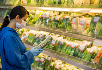 Young woman wears medical mask and protective gloves against coronavirus covid-19 while grocery shopping in supermarket or store- health, safety and pandemic outbreak concept