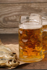 Close-up dried fish, vintage glass of beer on a dark wooden background. Vertical format
