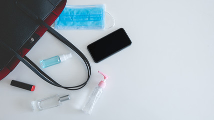 Flat lay of black leather women bag in outbreak situation open out with cosmetics, perfume,...