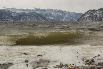 Shoreline of Teletskoye lake with thundering waves, in winter. Russia, Altai territory