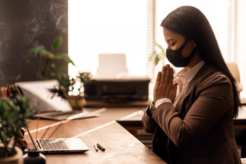 Online prayer. Church service. Asian woman praying wood table, laptop. Buddha. Spiritual. Buddhism. Meditation.