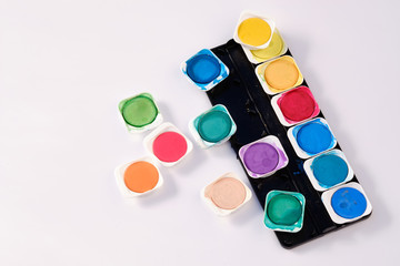 The bright variegated colours of a used watercolor box lying isolated on white background.