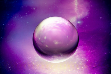 Crystal glass ball is lying on a stone surface on the colorful abstract background.