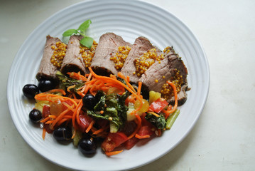 On a white plate, slices of chopped beef roast beef and salad with sauce