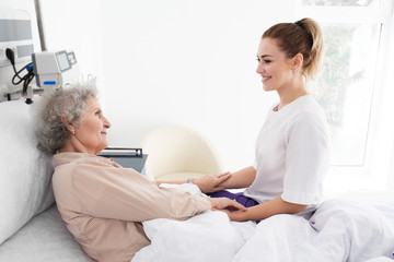 Woman with Alzheimer's disease lying in bed receives nurse care. Treating and caring for the elderly with Alzheimer's disease