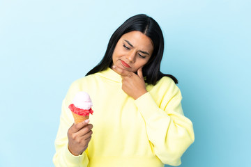 Young Colombian woman with a cornet ice cream isolated on blue background with sad expression