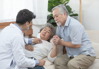 Fototapeta premium The young caucasian doctor listens to heartbeat by use a stethoscope with senior elderly old Asian female patients about disease symptoms, elderly health check-ups.