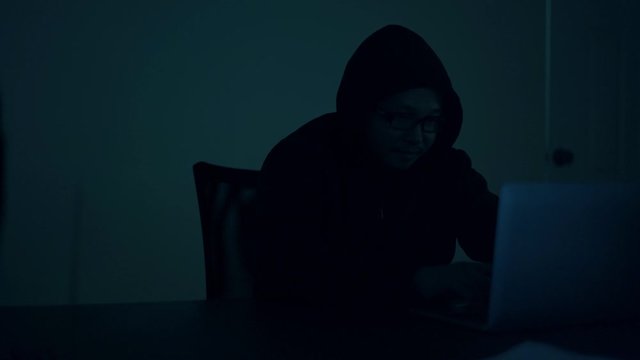 A computer programmer or hacker prints a code on a laptop keyboard to break into a secret organization system.