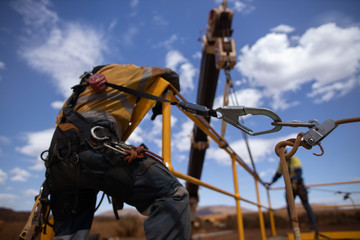 Safe workplace rigger wearing working at heights harness clipping an inertia reel shock absorbing...