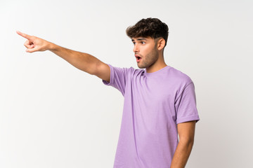 Young handsome man over isolated white background pointing away