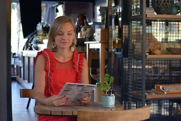 Sitting girl in a red dress reading the menu. Young girl sitting at a table in a cafe.Young beautiful girl in a cafe Marmaris    