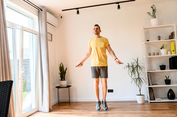 A guy in yellow t-shirt jumping rope at home
