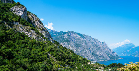 Fototapeta na wymiar Beautiful nature background. Panorama of the gorgeous Lake Garda surrounded by mountains. Scenic sight in Tremosine sul Garda, village on Lake Garda, in the Province of Brescia, Lombardy, Italy.