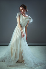 Emotional old-fashioned portrait of a girl in retro style in a light transparent dress with shiny elements on the shoulders.