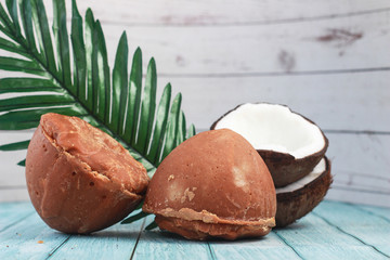 Jaggery or sugar from palm or coconut with half of coconut and leaf on wooden background
