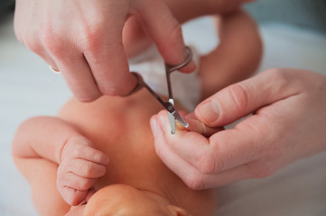 Father cuts the newborn’s nails. Manicure a child close-up. Newborn baby care concept.