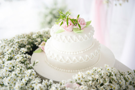 Elegant white wedding cake with flowers and succulents in dreamy style at wedding avenue reception.