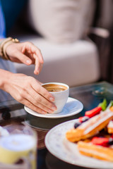 Women's hands reach for a cup of coffee
