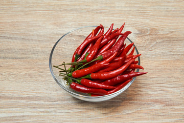 glass cup with pods of red hot pepper on a wooden table surface