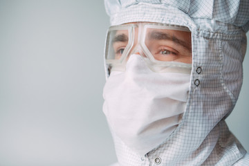 Portrait of a male doctor of European appearance in a medical mask, protective glasses and chemical suit.