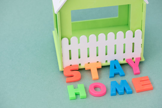 Green house with the inscription stay home in a coronavirus pandemic on paper background - Powered by Adobe