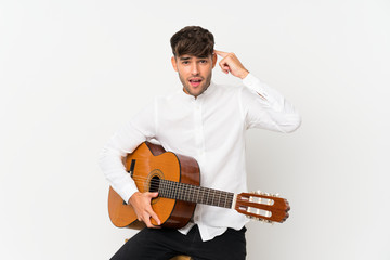 Young handsome man with guitar over isolated white background intending to realizes the solution