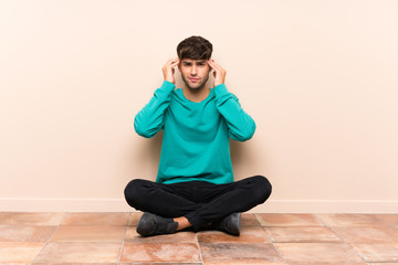 Young handsome man sitting on the floor unhappy and frustrated with something. Negative facial expression