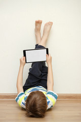 Modern generation. The child plays games or watches cartoons. The boy holds in his hands a tablet with a white screen for the layout.