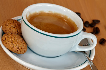 Coffee cup with biscuits and coffee beans on timber table